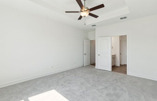 5917 Mayer Ave, Pilot Point, TX 75009 - unfurnished bedroom featuring light colored carpet, a tray ceiling, connected bathroom, baseboards, and ceiling fan