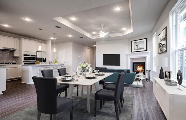 dining area featuring dark wood-style floors, visible vents, a tray ceiling, and ornamental molding