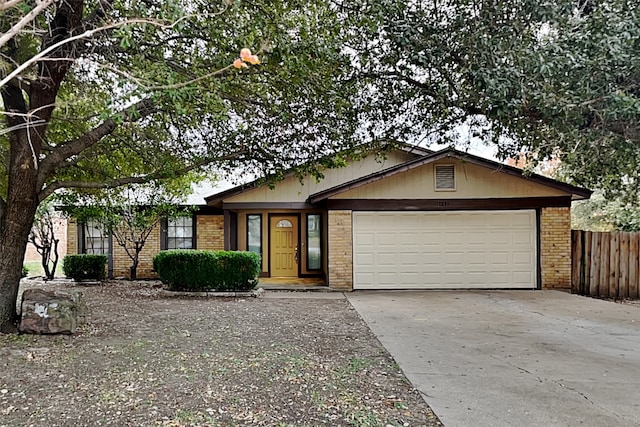 single story home featuring a garage, driveway, brick siding, and fence