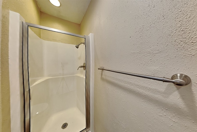 full bathroom featuring a textured wall and a shower stall