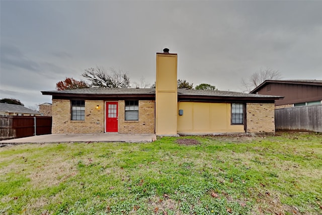 back of property with brick siding, a chimney, a patio area, and fence