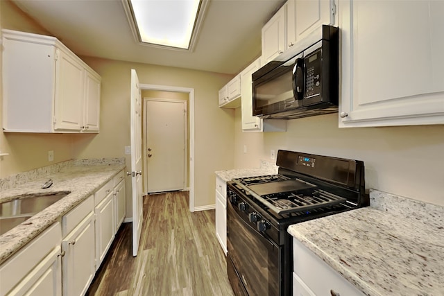 kitchen with light stone counters, light wood-style flooring, white cabinetry, baseboards, and black appliances