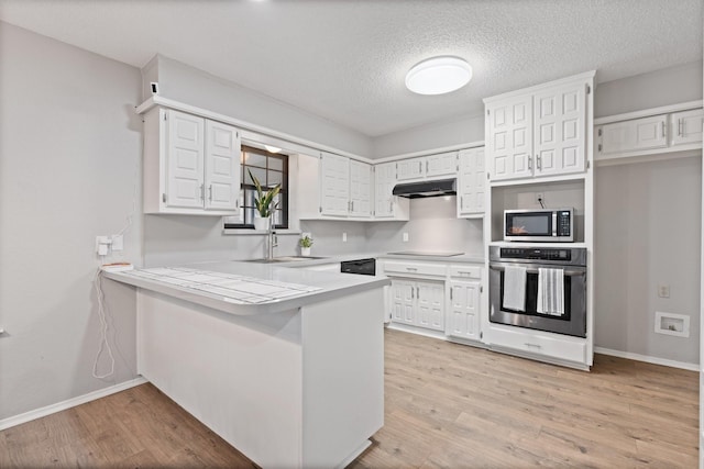 kitchen featuring a peninsula, white cabinetry, black appliances, and under cabinet range hood