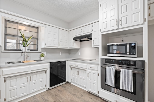 kitchen featuring light countertops, black appliances, white cabinets, and under cabinet range hood