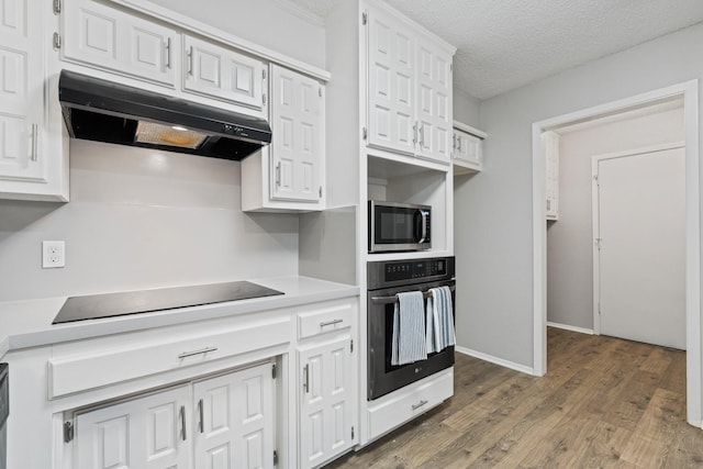 kitchen featuring under cabinet range hood, light countertops, white cabinets, dark wood-style flooring, and black appliances