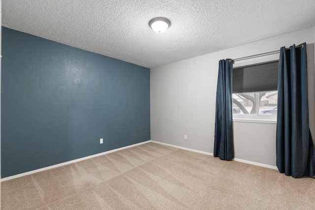 unfurnished room featuring baseboards, a textured ceiling, and light colored carpet