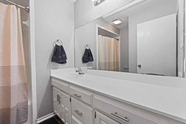 bathroom featuring shower / bath combo with shower curtain, vanity, and a textured wall