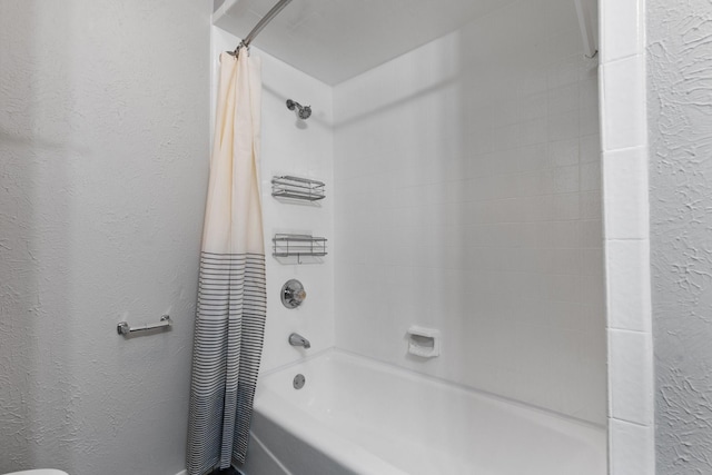 bathroom featuring a textured wall and shower / tub combo