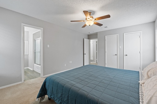 carpeted bedroom with ceiling fan, connected bathroom, baseboards, and a textured ceiling