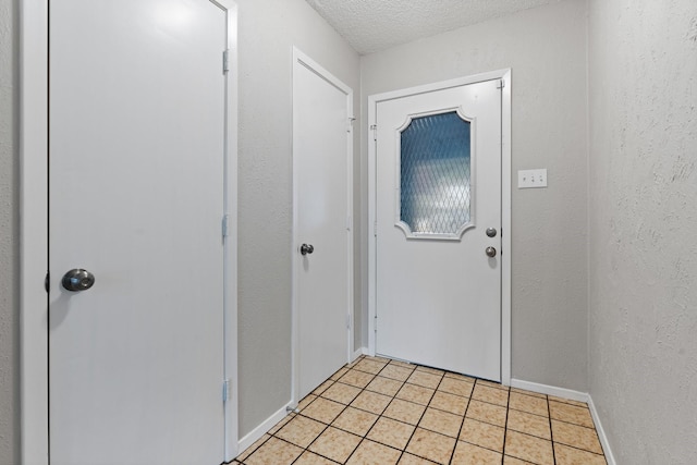 entryway with light tile patterned floors, baseboards, a textured ceiling, and a textured wall