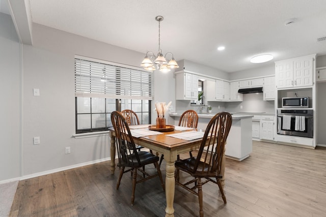 dining room with baseboards, visible vents, a chandelier, and light wood finished floors