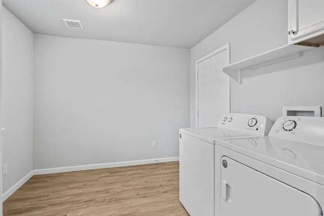 laundry area with cabinet space, baseboards, visible vents, washer and dryer, and light wood-type flooring