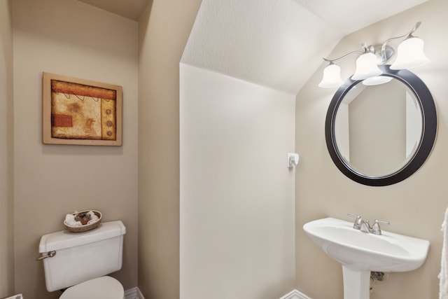 bathroom with vaulted ceiling, toilet, and a sink