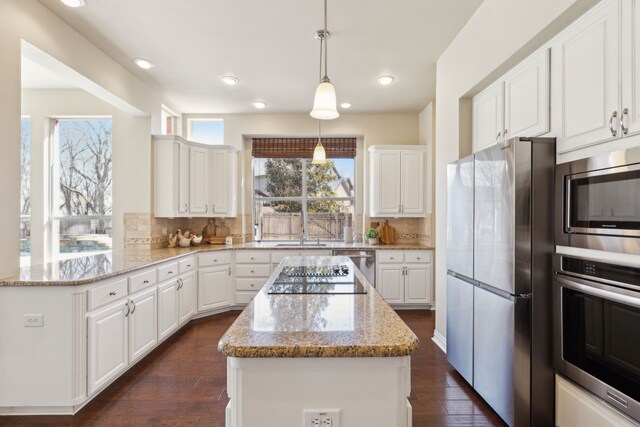 kitchen featuring a sink, light stone counters, backsplash, white cabinetry, and appliances with stainless steel finishes