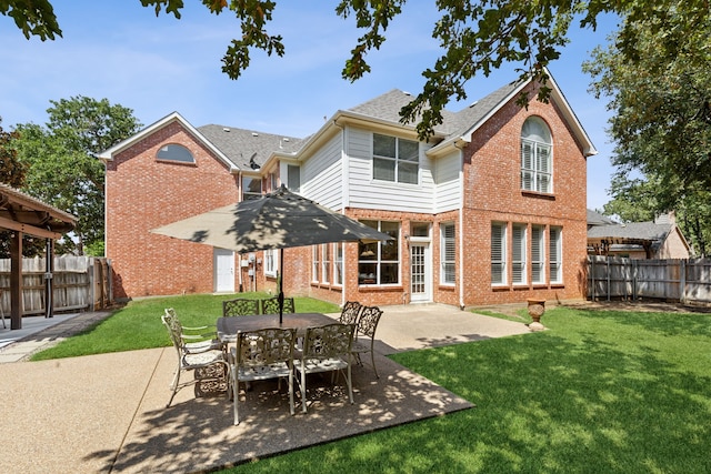 back of property with a patio, brick siding, a lawn, and fence