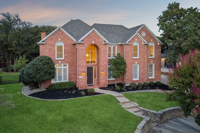 view of front of home featuring brick siding, a lawn, fence, and a chimney