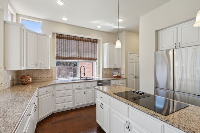 kitchen with a sink, dark wood-style floors, freestanding refrigerator, decorative backsplash, and black electric stovetop