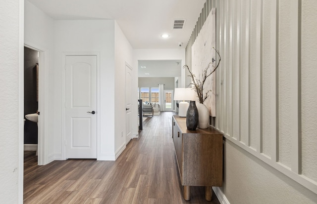 hall featuring baseboards, visible vents, wood finished floors, and recessed lighting