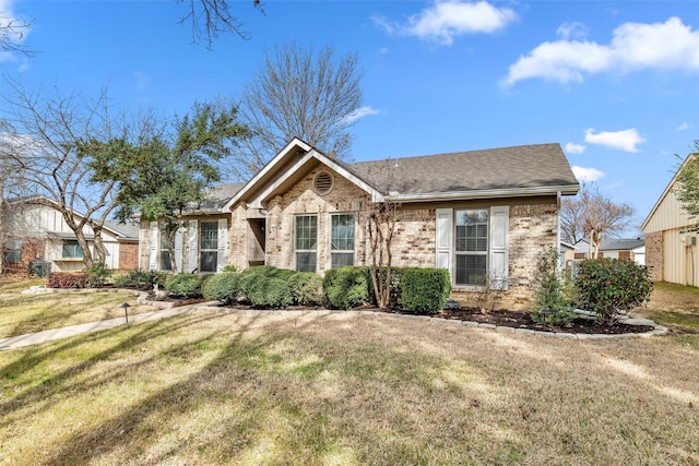 single story home with brick siding, a front yard, and a shingled roof