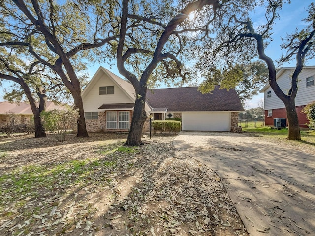 view of front of home with brick siding, concrete driveway, an attached garage, central AC, and fence