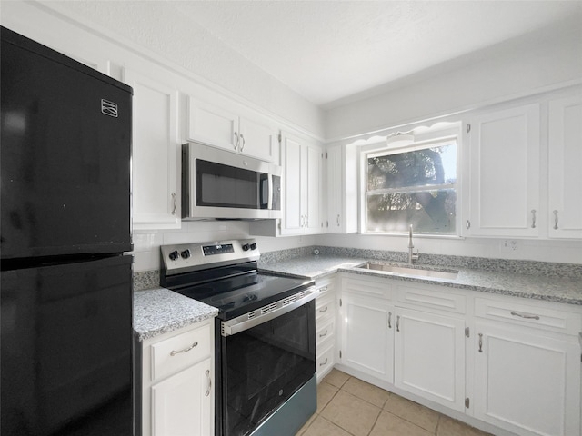 kitchen featuring stainless steel appliances, white cabinetry, a sink, and light tile patterned flooring