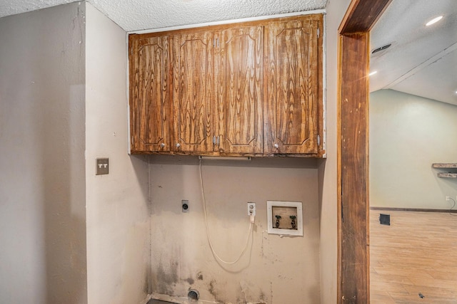 laundry room featuring wood finished floors, washer hookup, hookup for an electric dryer, a textured ceiling, and cabinet space