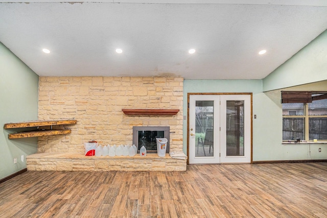 unfurnished living room featuring wood finished floors, baseboards, recessed lighting, a textured ceiling, and a fireplace