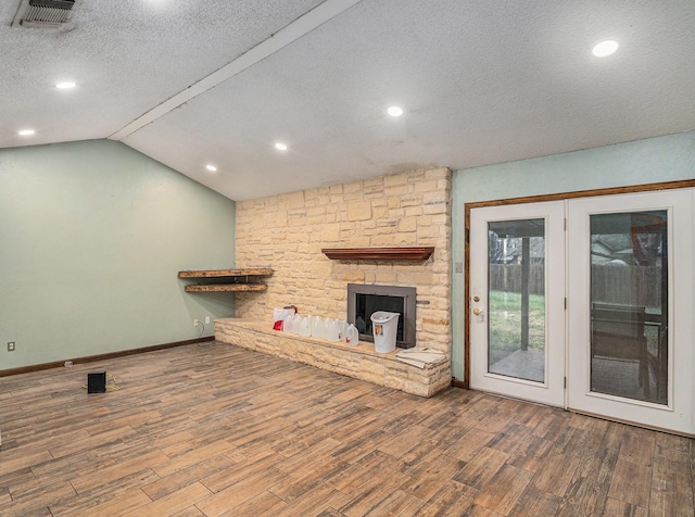 unfurnished living room featuring a textured ceiling, visible vents, wood finished floors, and lofted ceiling