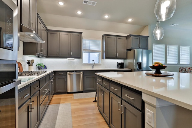 kitchen featuring appliances with stainless steel finishes, light countertops, hanging light fixtures, and visible vents