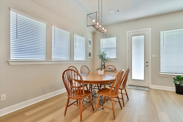 dining room with light wood-style floors, an inviting chandelier, visible vents, and baseboards