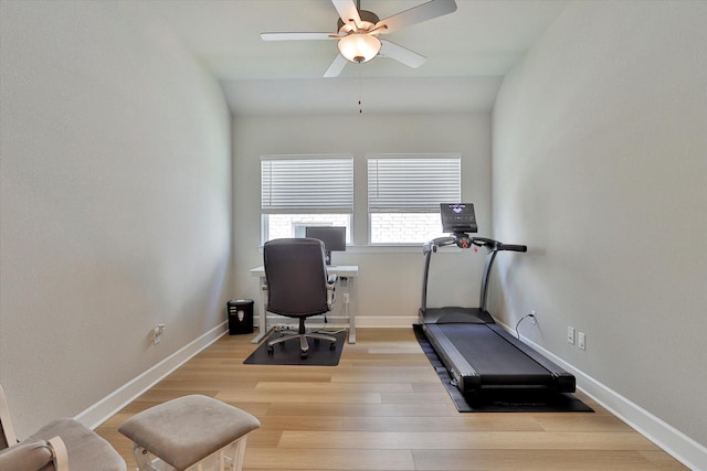 exercise area featuring light wood-style floors, ceiling fan, baseboards, and vaulted ceiling