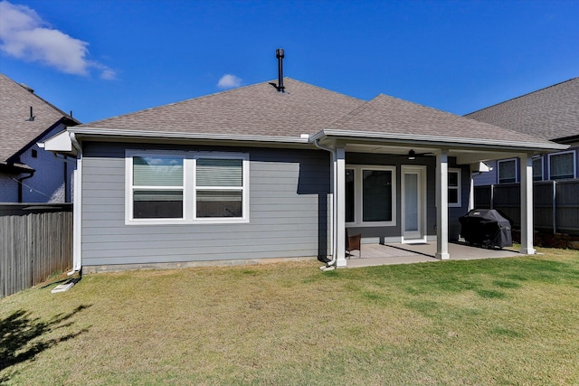 back of property featuring ceiling fan, a shingled roof, fence, a yard, and a patio area