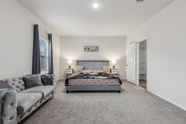 bedroom with light carpet, a spacious closet, visible vents, and baseboards