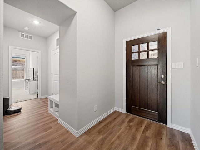 entrance foyer featuring baseboards, visible vents, and wood finished floors