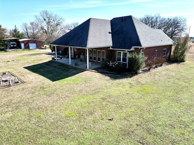 back of property with a patio, brick siding, a shingled roof, a yard, and a carport