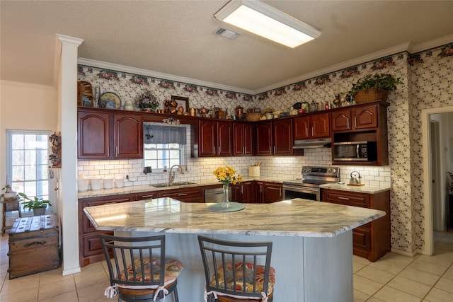 kitchen featuring a center island, crown molding, a breakfast bar area, stainless steel appliances, and a sink