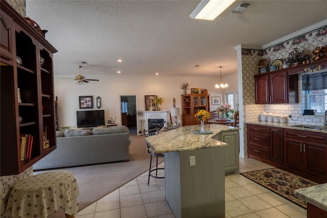 kitchen featuring a kitchen island, a kitchen breakfast bar, open floor plan, pendant lighting, and a sink