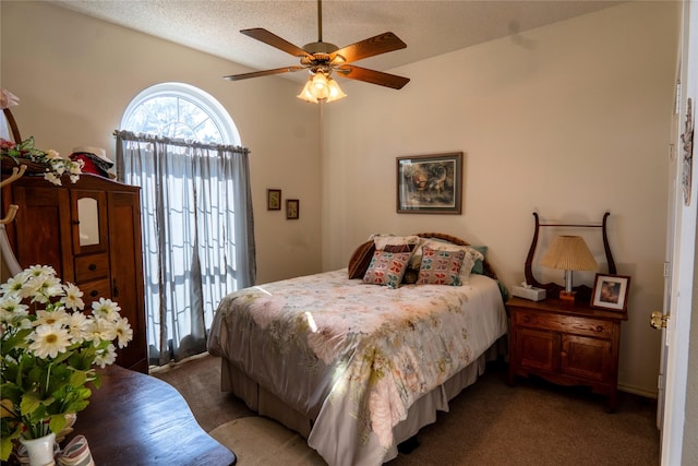 bedroom featuring ceiling fan, dark carpet, and a textured ceiling