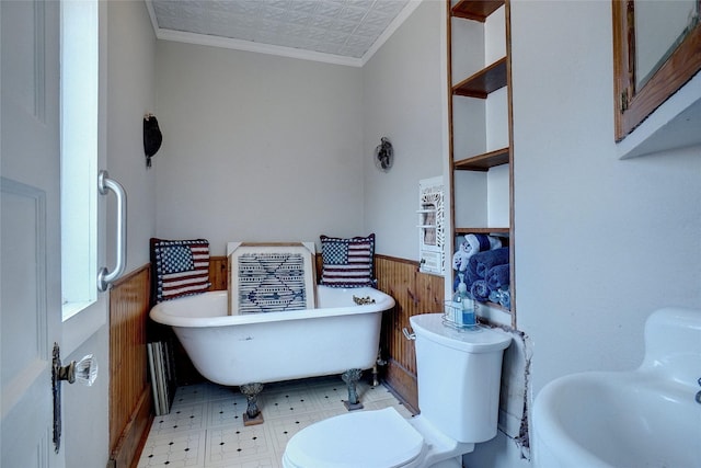 bathroom featuring wooden walls, a wainscoted wall, a freestanding bath, tile patterned floors, and crown molding