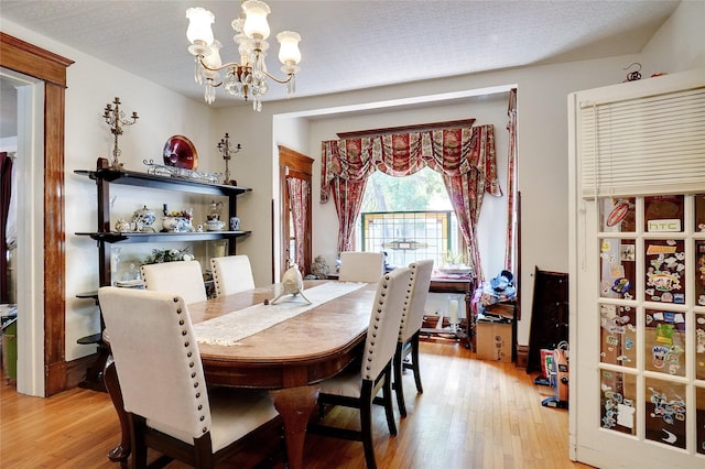 dining space with light wood-type flooring and a notable chandelier