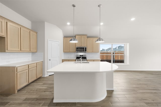 kitchen with a sink, appliances with stainless steel finishes, light brown cabinetry, and light countertops