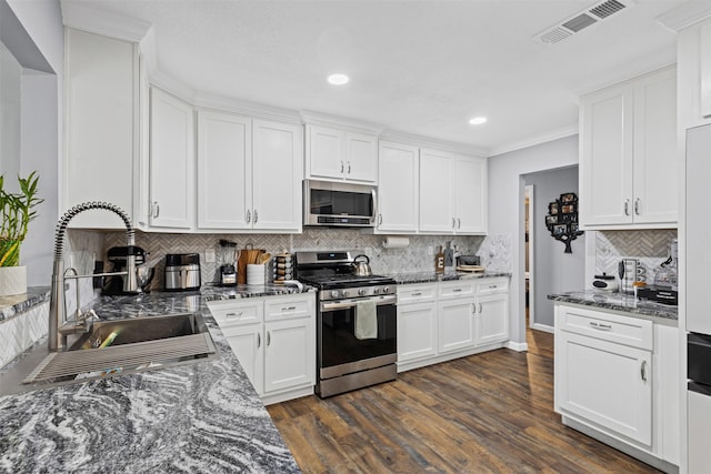 kitchen featuring a sink, visible vents, white cabinetry, appliances with stainless steel finishes, and dark stone countertops