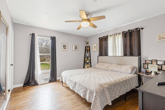 bedroom with wood finished floors, a ceiling fan, and baseboards