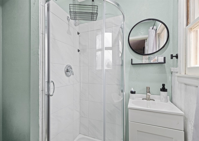 full bath with a textured wall, a stall shower, and vanity