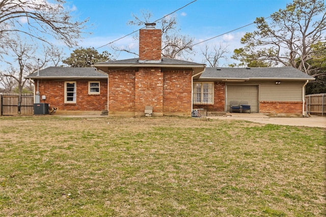 rear view of house with a garage, fence, a chimney, and a lawn