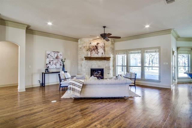 living room featuring arched walkways, ornamental molding, and dark wood-style floors