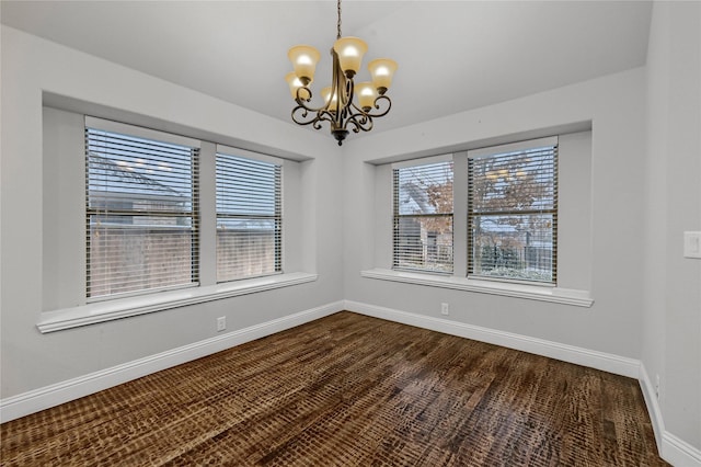 unfurnished dining area featuring baseboards and an inviting chandelier