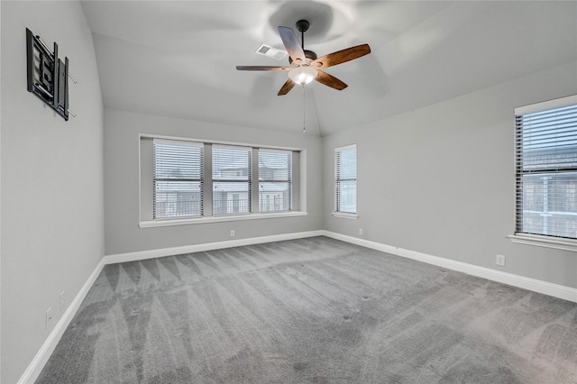 empty room featuring lofted ceiling, baseboards, a wealth of natural light, and light colored carpet