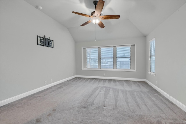 empty room with light carpet, ceiling fan, baseboards, and vaulted ceiling