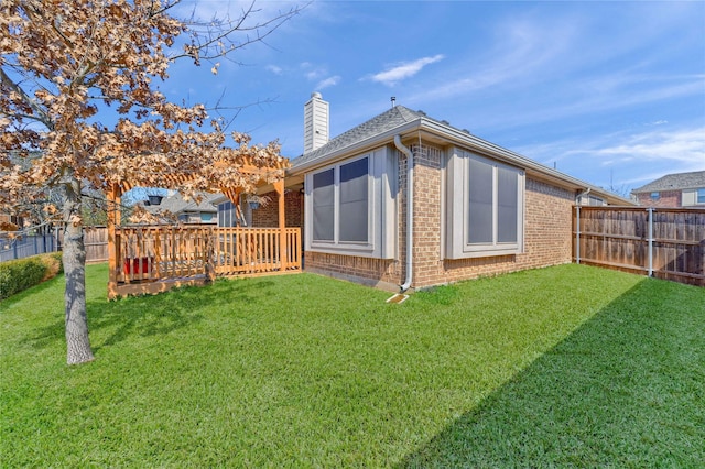 rear view of property featuring brick siding, a lawn, a chimney, and a fenced backyard